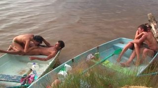 Horny people are having group sex on the beach in a small boat