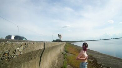 The girl undresses, walks and masturbates near the road by the lake