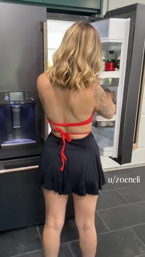 Woman in black and red bikini top standing in front of refrigerator