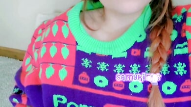 Young woman in festive sweater explores herself on the carpet
