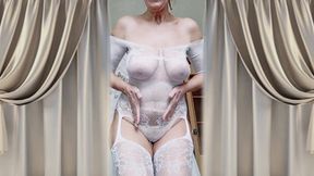 Cheerful housewife Lukerya flirts in an open, transparent white jumpsuit in the kitchen.