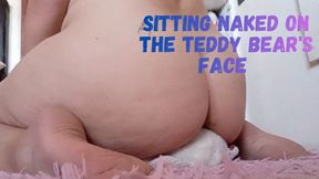 Sitting naked on the teddy bear's face