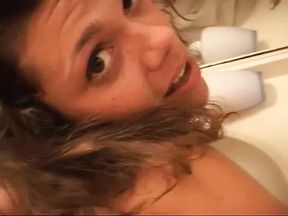 Cute young brunette licks her own tits and gets fucked from behind in bathroom
