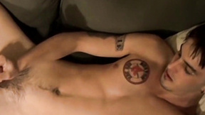 Deviant young man with tattoos strokes his big unshaved prick