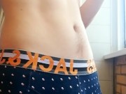 a guy with a beautiful body and a big dick in panties smokes on the balcony