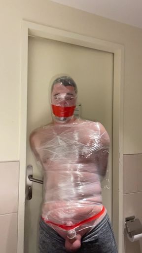 german twink slave securely wrapped and gagged in plastic wrap mummification bondage in a hotel room