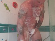 Muscular tattooed guy takes hot shower after the gym