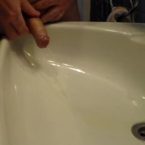John is peeing into the bathroom sink