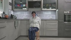 Miss Amira tied to a chair in a Farmerrain rain suit