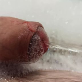 Close up pissing cock in the foam in bathtub