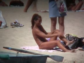 Horny naked brunette woman teasing her mates on the beach