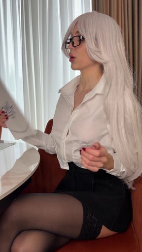 Blonde woman in white shirt and glasses sitting in chair