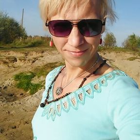 Trans girl swimming in the lake in clothes blue blouse and white-milk pants.