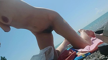skinny nutist eats a peach on the beach