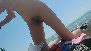 skinny nutist eats a peach on the beach