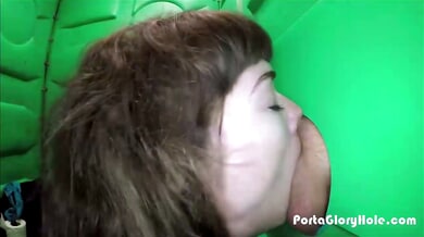 Woman performs oral sex through a glory hole in a public outdoor booth