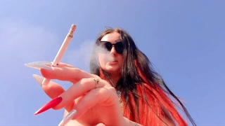 Smoking fetish. Dominatrix smokes a cigarette on the beach