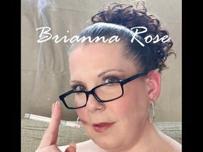 Sitting in a sheer flowered blouse, black bra and lacy pants smoking a VS 120