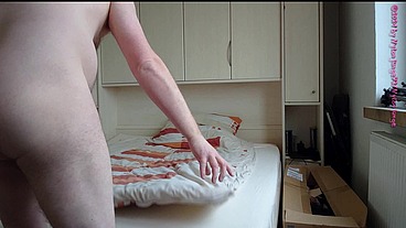 Nackter Nylonjunge bezieht sein Bett