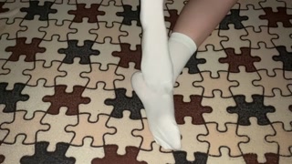 Sexy legs in white socks rub against each other in bed