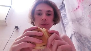 Nude damsel munches burger while on the rest room