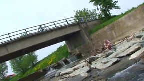 Blonde pissing outside in a river