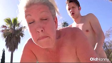 Busty blonde granny gives a blow job by the pool