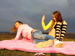 Two horny young lesbians masturbate together in the outdoors