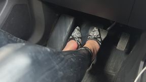 A girl in high-heeled shoes drives a car on the road