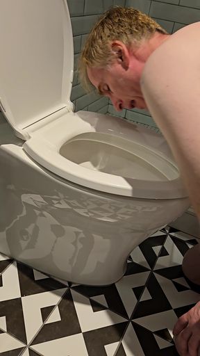 Gay BDSM slave kneeling naked in a Vancouver hotel licking the toilet for humiliation.