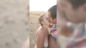 Blond babe gets mouth and hand on dude on beach as waves crash