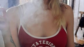 European girl smoking a cigarette at home in streetwear outfit