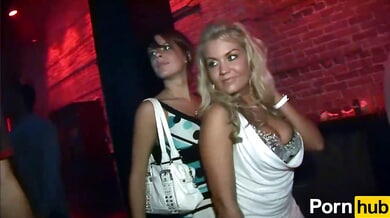 Two women tease the crowd with a steamy skirt-lifting dance at a neon-lit club