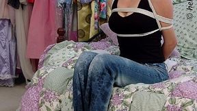 Tied and gagged in her top and jeans, perky little Noelle Nash sits struggling on a bed, then lies barefoot on her side!