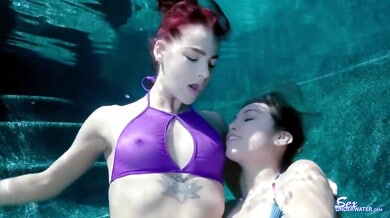 Redheaded woman receives cunnilingus underwater from a dark-haired partner