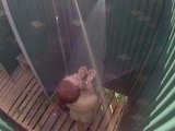 Adorable girl is taking a bath in a public shower on the beach, in front of the camera
