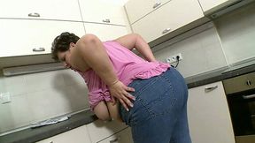 Mature white BBW housewife in jeans and purple blouse in the kitchen