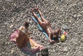 Adorable bronze skin shiny brunette sunbathing on the beach nude