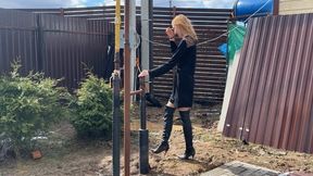 girl in high-heeled leather boots walks through a mud pit where the mud is knee-deep