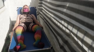 Caged sissy plays with her dildo on public balcony