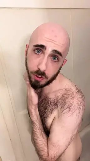 Very hairy skinny blue-eyed white guy shaves his head in the showet