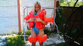 Christina in Realise swimsuit deflates life vests and arm wings outdoors