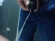 Locked in a chastity cage, man is pissing in a public toilet
