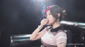 Asian Woman Smoking Cigarette Blowing Thick Smoke Rings and Deep Inhales on Leather Couch — QI1 4K