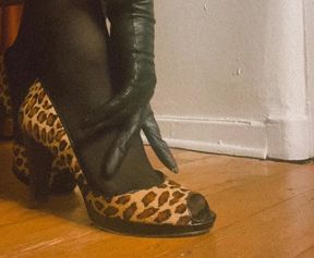 Mistress puts on high heels while wearing black leather gloves