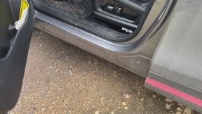 A girl in leather boots was driving a car and her car got stuck in the mud and doesn't want to drive anymore, she has to push it