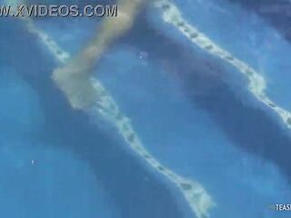 Disinterested lesbian companions are engaging in inappropriate behavior in the outdoor pool while sunbathing.