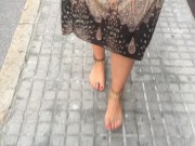 young female hippie is walking barefoot in public street