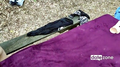 Lovers explore passion in a secluded forest clearing with a purple blanket spread under the trees