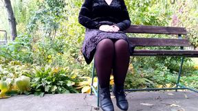 Peeing with legs spread wide on a bench in an autumn park